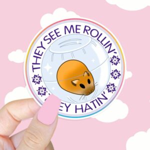 A graphic of They See Me Rolling Hamster Sticker available on HeckinMagical.com