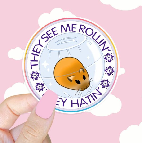 A graphic of They See Me Rolling Hamster Sticker available on HeckinMagical.com