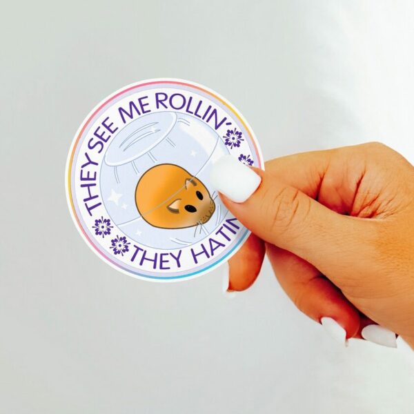 A graphic of They See Me Rolling Hamster Sticker available on HeckinMagical.com