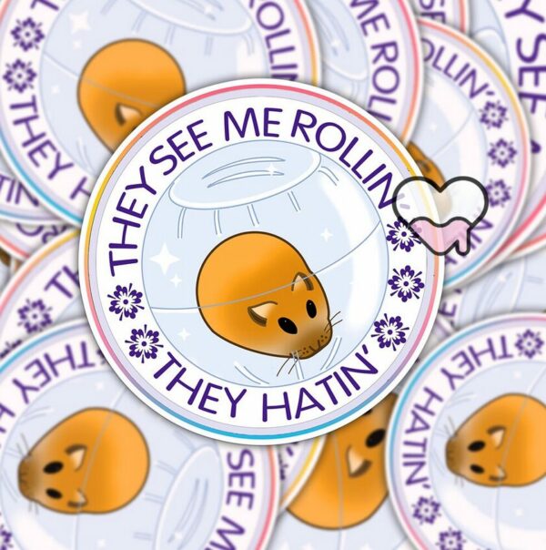 A graphic of They See Me Rolling Hamster Sticker available on HeckinMagical.com